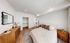 Bright and inviting bedroom with elegant decor, featuring a spacious bed, chic wooden dresser, and open closet in a modern apartment.