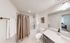 Elegant bathroom featuring a modern vanity, white countertops, and a relaxing shower-tub combo with stylish curtains.