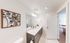 Sleek and modern bathroom showcasing a dual-sink vanity with elegant fixtures and a tasteful floral wall art, opening into a cozy, sunlit living room.