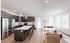 Modern open-concept kitchen and living room with sleek dark cabinetry, stainless steel appliances, and abundant natural light.