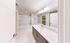 Bright and modern bathroom featuring a sleek vanity with ample storage, elegant lighting fixtures, and a spacious bathtub.