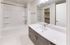 Sleek modern bathroom with a large vanity, stylish mirror, and spacious bathtub in a luxurious apartment.