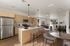 Bright and modern open-plan kitchen and living area featuring sleek wooden cabinets, stainless steel appliances, and elegant lighting fixtures, perfect for stylish entertaining.