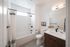 Bright, modern bathroom with elegant fixtures, featuring a spacious bathtub, sleek vanity with potted flowers, and a large mirror.