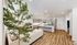 Modern open-concept living space featuring a chic kitchen with island seating, cozy lounge area, and elegant wooden flooring.
