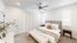 Elegant bedroom with plush bedding, modern gray headboard, and cozy decor, illuminated by soft natural light through vertical blinds.