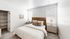 Bright and cozy bedroom with plush carpet, featuring a stylish wooden bed frame, elegant side tables, and ample closet space.
