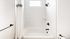 Sleek and modern bathroom with pristine white tiles, elegant black fixtures, and a stylish shower area.
