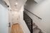 Bright and inviting hallway featuring elegant light wood flooring and modern staircase with sleek black railing.