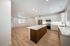 Modern open-concept living space featuring a sleek kitchen with stainless steel appliances, elegant cabinetry, and a large island, seamlessly flowing into a bright, spacious living area with stylish wood flooring.