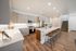 Bright and modern kitchen with sleek cabinetry, spacious island, and elegant bar stools, complemented by warm wood flooring.