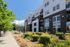 Contemporary apartment building with stylish architecture, lush landscaped entrance, and sunny skies, offering a vibrant urban living experience.