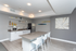 Modern kitchen space with sleek white cabinetry, chic open shelving, stylish island seating, and contemporary decor.