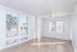 Bright and airy living room with large windows, sleek hardwood floors, and a modern ceiling fan.