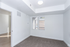 Bright and airy room with plush carpeting, large windows, and modern lighting, perfect for a cozy living space or home office.