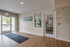 Bright and welcoming apartment entrance with sleek hardwood floors and a view into the modern fitness center, perfect for active living.