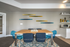 Modern dining area with sleek wooden table, stylish blue chairs, and abstract wall art, perfect for contemporary living.