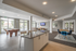 Chic communal space with modern kitchen island, stylish seating, pool table, and large windows for natural light.