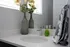 Modern bathroom with elegant countertop, stylish faucet, and decorative vase with flowers.