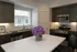 Modern kitchen with sleek dark cabinets, white countertop island, and stainless steel appliances illuminated by natural light.