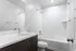 Modern, sleek bathroom featuring a pristine white bathtub, elegant vanity with under-sink storage, and minimalist design accents.