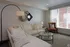 Chic and cozy living room with elegant white sectional sofa, stylish accent pillows, and modern decor. Bright natural lighting from large windows enhances the inviting atmosphere.