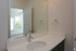 Elegant bathroom featuring a sleek modern sink, large mirror, and ample natural light from the adjacent room.