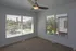Bright corner room with large windows showcasing serene outdoor views and modern ceiling fan.