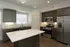 Modern kitchen with sleek dark cabinetry, stainless steel appliances, and a spacious island with a pristine white countertop, designed for contemporary living.