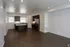Modern open-concept kitchen and living area featuring sleek dark wood flooring, stainless steel appliances, and ample natural light.