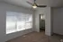 Bright, inviting bedroom featuring modern ceiling fan, plush carpeting, and ample natural light from large window with blinds.