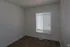 Bright empty room with large window and carpeted floor, perfect for bedroom or office space.