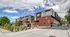 Modern apartment complex with sleek architecture and natural landscaping under a vibrant sky.