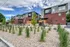 Modern apartment complex featuring sleek architectural design with red brick and gray paneling, surrounded by landscaped greenery and vibrant sky.