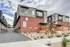 Modern townhouses featuring sleek architectural design with brick and panel exteriors, nestled in a landscaped urban setting.