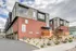 Modern apartment complex featuring sleek architecture with red brick and stylish gray paneling, surrounded by well-maintained landscaping under a partly cloudy sky.