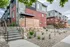 Modern townhouse facade with stylish brick and panel design, featuring a welcoming entrance and landscaped front yard with greenery and stone accents.