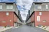 Modern townhouse complex with sleek red brick and gray facade, featuring spacious garages and a clear blue sky backdrop.