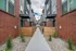 Modern apartment complex with stylish red brick fa&ccedil;ades, featuring a clean concrete walkway and cozy wooden fenced patios.