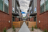 Contemporary urban apartment complex with modern architecture, featuring stylish brick and wood details along a landscaped pathway.