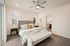 Elegant bedroom with a plush bed, neutral decor, and soft lighting, featuring a ceiling fan and a cozy ambiance.
