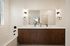 Elegant modern bathroom featuring a sleek double vanity with wood cabinetry, stylish black fixtures, and soft overhead lighting.