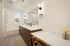 Modern bathroom featuring a sleek double vanity with wooden cabinets, bright lighting, and a cozy bathtub with subway tiles.