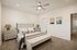 Elegant bedroom with neutral tones featuring a chic bed with plush pillows, stylish bedside tables, modern ceiling fan, and ambient lighting for a cozy atmosphere.