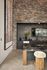 Sophisticated industrial kitchen showcasing a luxurious stone wall, sleek dark cabinetry, and a chic marble island with plush stool seating.