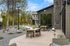 Elegant outdoor patio with modern seating, surrounded by lush greenery and a stylish brick facade, perfect for al fresco dining.