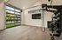 Modern home gym with sleek exercise equipment and floor-to-ceiling glass doors, opening to a lush garden view.