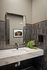 Modern bathroom with elegant dark tile accent wall, stylish rectangular mirror, and sleek marble countertop.