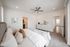 Elegant and airy bedroom with plush bedding, modern ceiling fan, and stylish decor, showcasing a harmonious blend of comfort and sophistication.