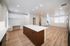 Modern open kitchen and living area with sleek white cabinetry, a stylish island, and elegant wood flooring.